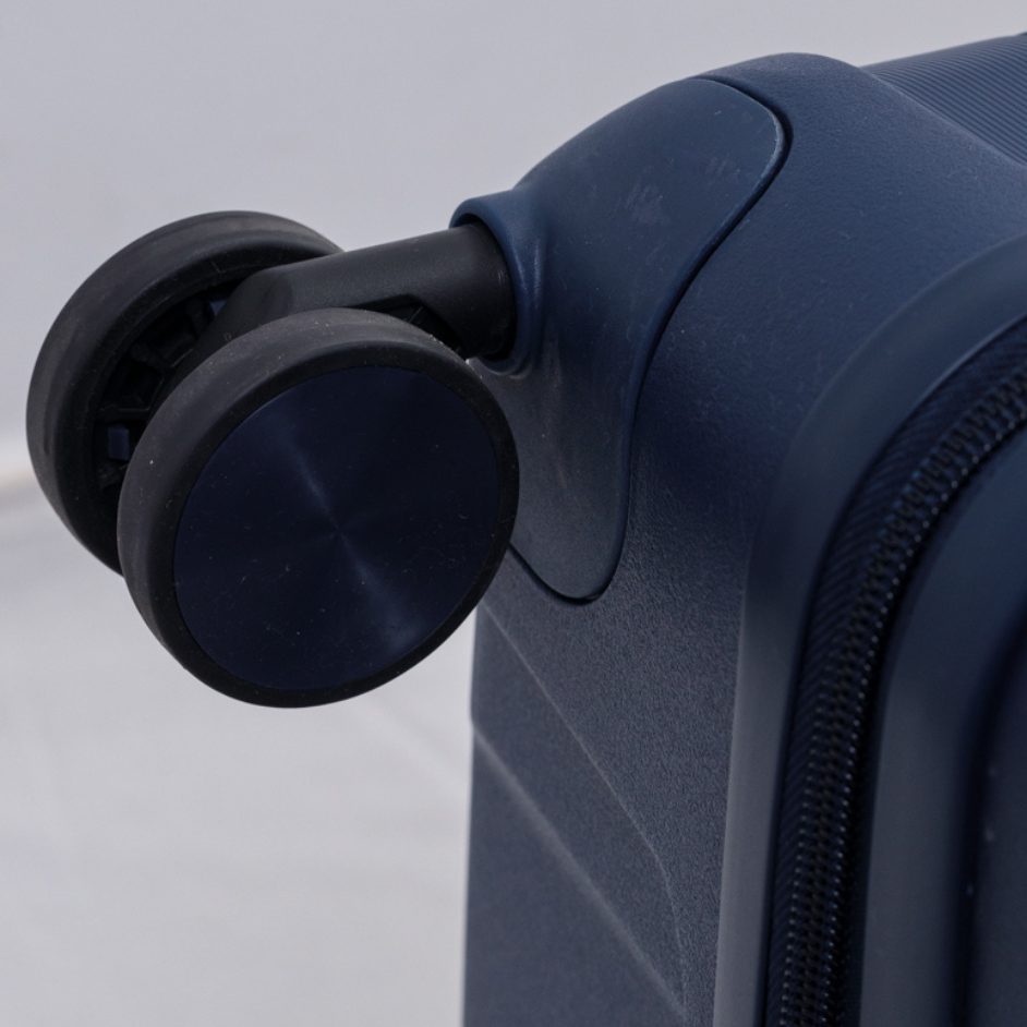 Primer plano de las ruedas dobles de una valija azul, mostrando la textura del borde inferior.